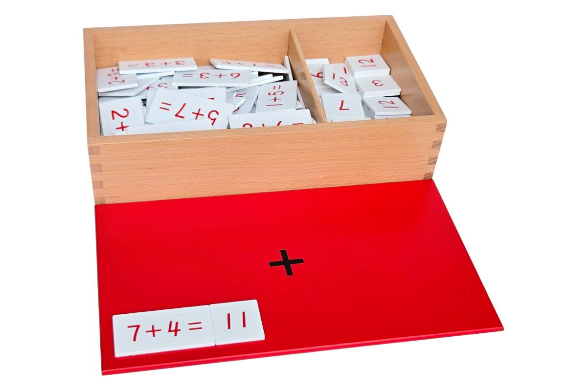 Addition equations and sums box with red lid printed with "+" containing white tiles with red text.