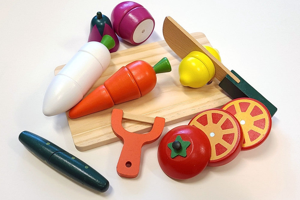 Parts laid out on a cutting board. The knife is midway through cutting a lemon into sections. The tomato is already sliced. Its magnets are visible.