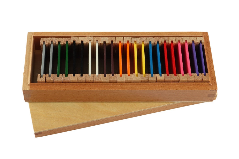 Second colour tablet box with one long rectangular compartment. Contains eleven pairs of tablets in the colours red, pink, yellow, white, black, blue, grey, green, orange, purple, and brown. The lid rests beneath the box.